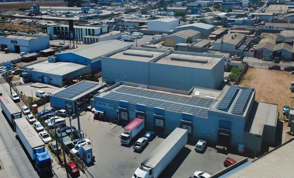 Paneles solares instalados sobre los techos del complejo de Master Frío en Coquimbo, con andenes de carga y camiones refrigerados en el patio